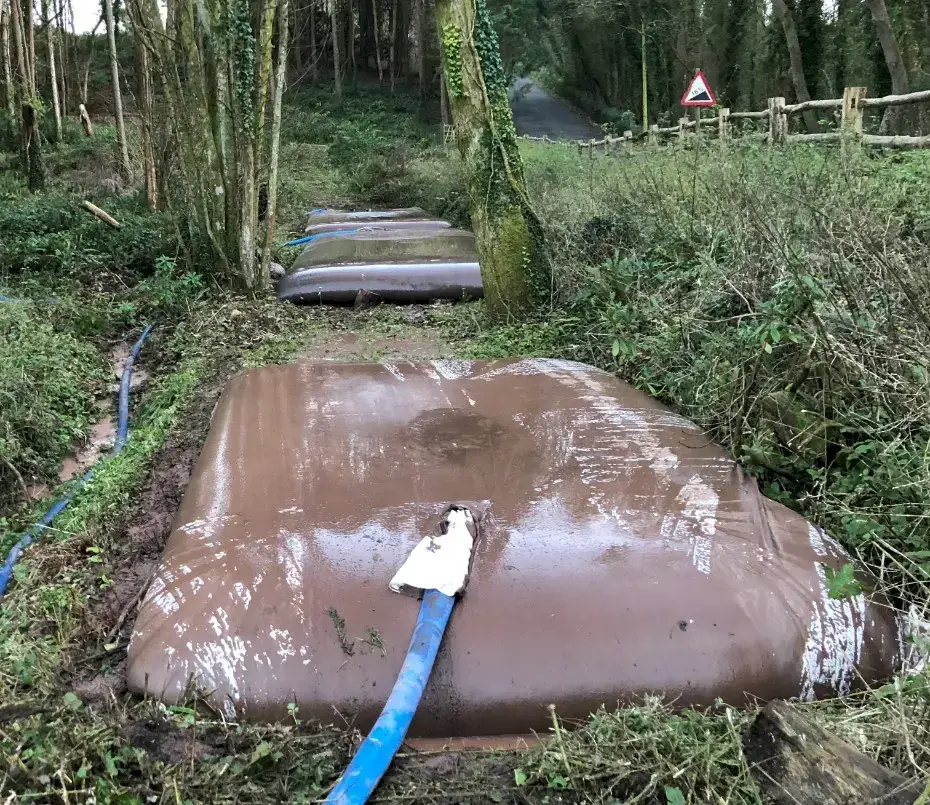 Grab bucket removing accumulated silt from a brook feeding into a restored pond